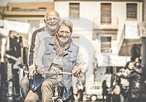 Happy retired senior couple having fun with bicycle at flea market