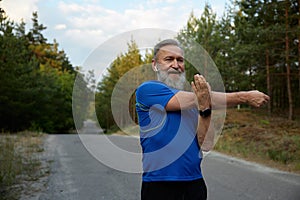 Happy retired sportsman stretching arms before running race start