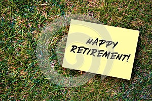 Happy retirement message written on yellow paper on green grass