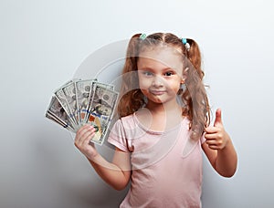 Happy rich kid girl holding money and showing thumb up sign