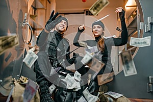 Happy robbers throwing money at the vault