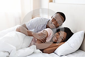 Romantic black couple bonding in bed at home