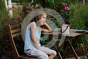 Happy romantic child girl dreaming in evening summer garden