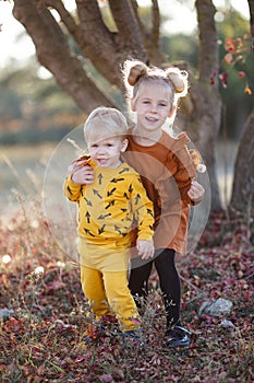 Happy romantic children boy and girl play together in the autumn park on a warm evening at sunset