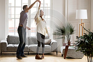 Happy romantic couple dancing in living room at home together