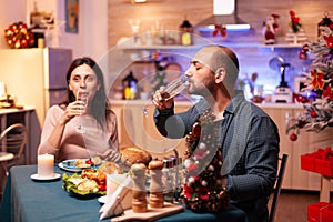 Happy romantic couple drinking wine while sitting at dinning table