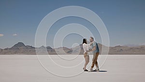 Happy romantic couple enjoy good time together on vacation, man holding woman in arms at sunny hot Utah salt desert lake