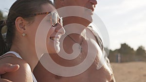 Happy romantic couple middle age man and his young wife enjoying a beautiful walk at sunset on the beach