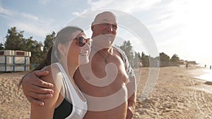 Happy romantic couple middle age man and his young wife enjoying a beautiful walk at sunset on the beach