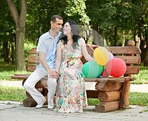 Happy romantic couple sit on bench in city park and posing, summer season, adult people man and woman