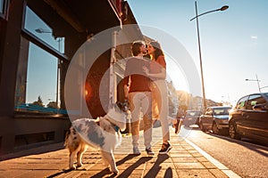 Happy romantic couple walking on the street with purebred dog Aussie. Pet training. Friendship with pet. Sunset light in