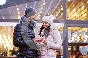 Happy romantic couple wearing warm clothes enjoying spending time together on a date in evening street near a cafe