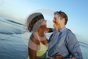 Happy and romantic mixed race couple with attractive black African American woman and Caucasian man playing on beach having fun