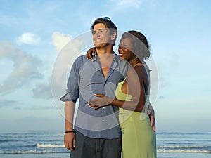 Happy and romantic mixed race couple with attractive black African American woman and Caucasian man playing on beach having fun