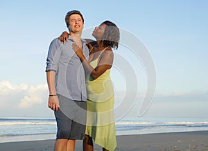 Happy and romantic mixed race couple with attractive black African American woman and Caucasian man playing on beach having fun