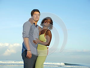 Happy and romantic mixed race couple with attractive black African American woman and Caucasian man playing on beach having fun