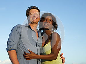 Happy and romantic mixed race couple with attractive black African American woman and Caucasian man playing on beach having fun