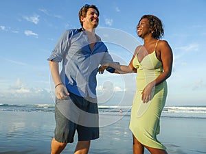 Happy and romantic mixed race couple with attractive black African American woman and Caucasian man playing on beach having fun