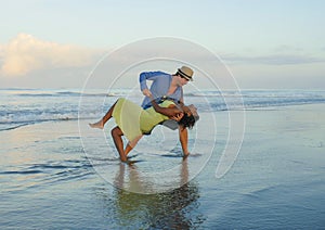 Happy and romantic mixed race couple with attractive black African American woman and Caucasian man playing on beach having fun