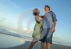 Happy and romantic mixed race couple with attractive black African American woman and Caucasian man playing on beach having fun
