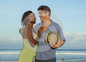 Happy and romantic mixed race couple with attractive black African American woman and Caucasian man playing on beach having fun