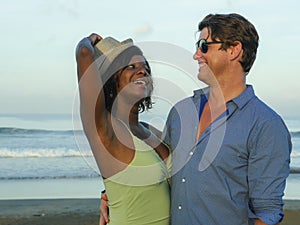 Happy and romantic mixed race couple with attractive black African American woman and Caucasian man playing on beach having fun