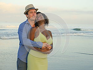 Happy and romantic mixed race couple with attractive black African American woman and Caucasian man playing on beach having fun