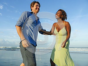 Happy and romantic mixed race couple with attractive black afro American woman and white man playing on beach having fun enjoying