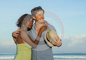 Happy and romantic mixed race couple with attractive black afro American woman and white man playing on beach having fun enjoying