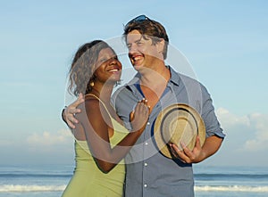 Happy and romantic mixed race couple with attractive black afro American woman and white man playing on beach having fun enjoying
