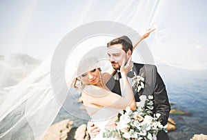 Happy and romantic scene of just married young wedding couple posing on beautiful beach