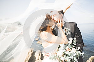 Happy and romantic scene of just married young wedding couple posing on beautiful beach