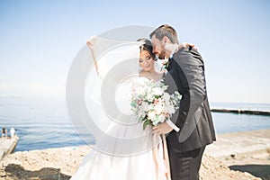 Happy and romantic scene of just married young wedding couple posing on beautiful beach