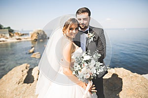 Happy and romantic scene of just married young wedding couple posing on beautiful beach