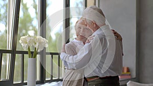 Happy romantic senior couple hugging and enjoying retirement at home