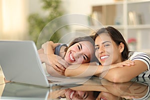Happy roommates with laptop looking at you photo