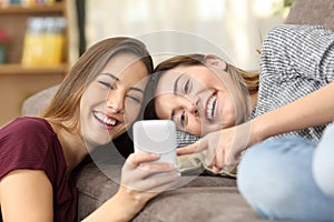Happy roommates watching on line content in a phone