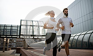 Happy runner couple exercising outside as part of healthy lifestyle. People sport running concept