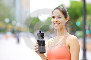 Happy runner holding water bottle after sport