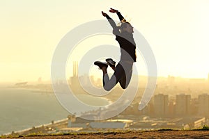 Happy runner jumping celebrating success at sunset