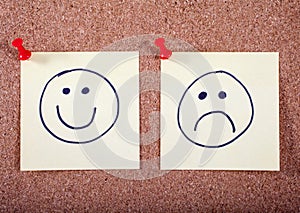 Happy and Sad Faces Pinned to a Noticeboard photo