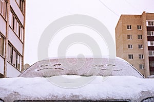 Happy and sad smiley emoticon face in snow on car windows, winter season joy and happiness concept