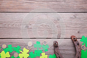 Happy Saint Patrick`s of handmade paper clover leaves, horseshoe and coins on grey wooden background