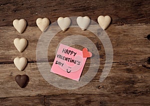 Happy Saint valentines day with post it note and heart shaped chocolate frame on wooden table