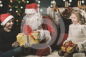 Happy Santa Claus and children around the decorated Christmas tree