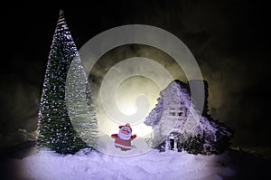 Happy Santa Claus Doll on Christmas time with tree and snow. Colorful bokeh background. Santa Clause and Merry Christmas model fig