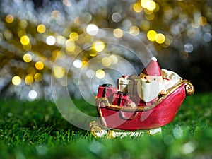 Happy Santa Claus with gifts box on the snow sled the background is Christmas decor.Santa Claus and Christmas decor on Green grass