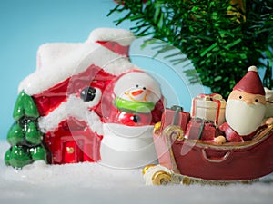 Happy Santa Claus with gifts box on the snow sled going to snow house. near snow house have Snowman and Christmas Tree.