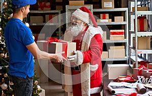Happy Santa Claus giving parcel gift box to courier, fast christmas delivery.