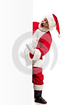 Happy Santa Claus pointing on blank advertisement banner background with copy space. Smiling Santa Claus pointing in